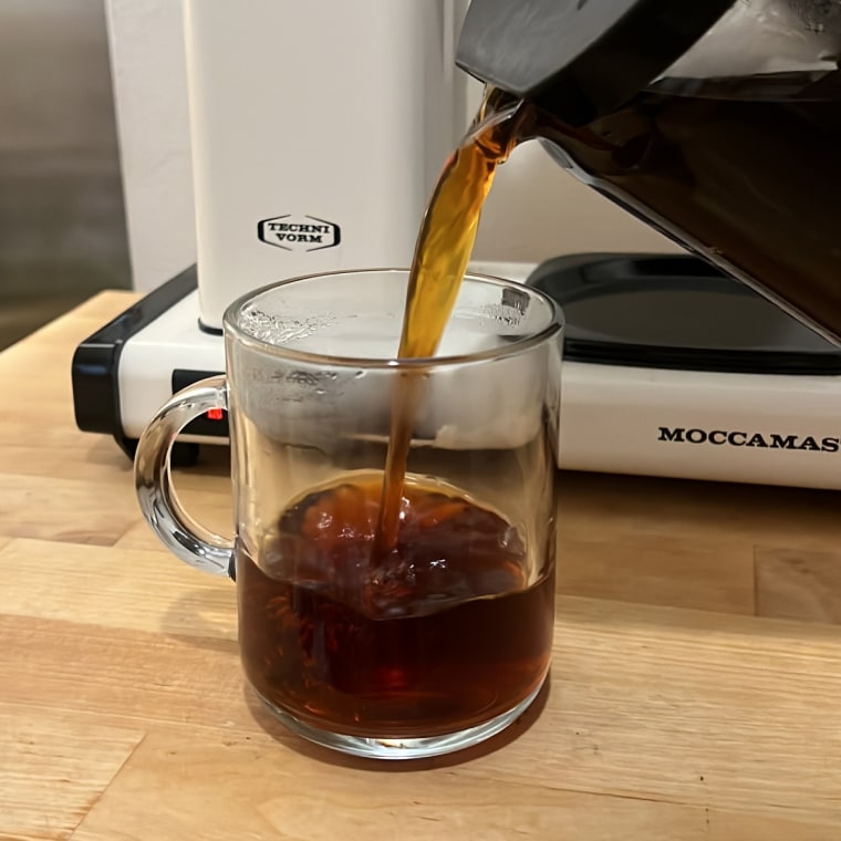 Black coffee poured into a glass mug on a wooden table