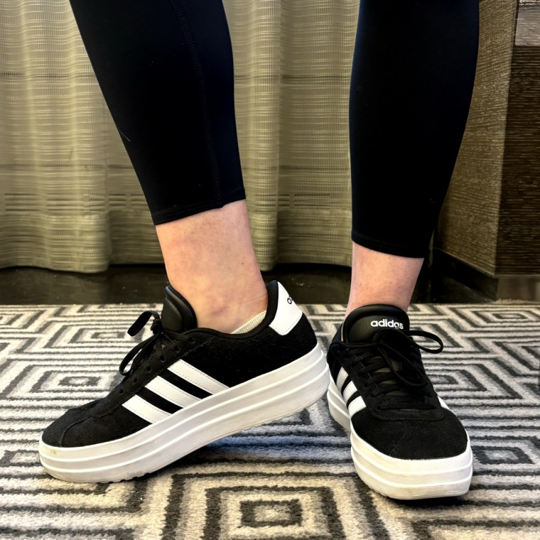 Woman wearing black and white Adidas VL Court Bold Platform Sneakers with black leggings in a living room.