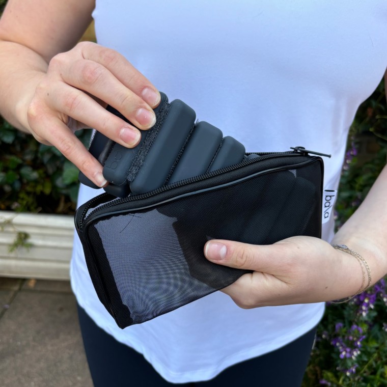 A woman in a white shirt taking black Bala Bangles out of a black mesh carrying case.