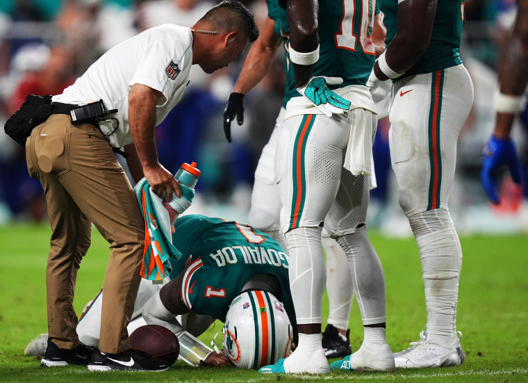 A member of the Miami Dolphins training staff attends to Tua Tagovailoa after he suffered a concussion