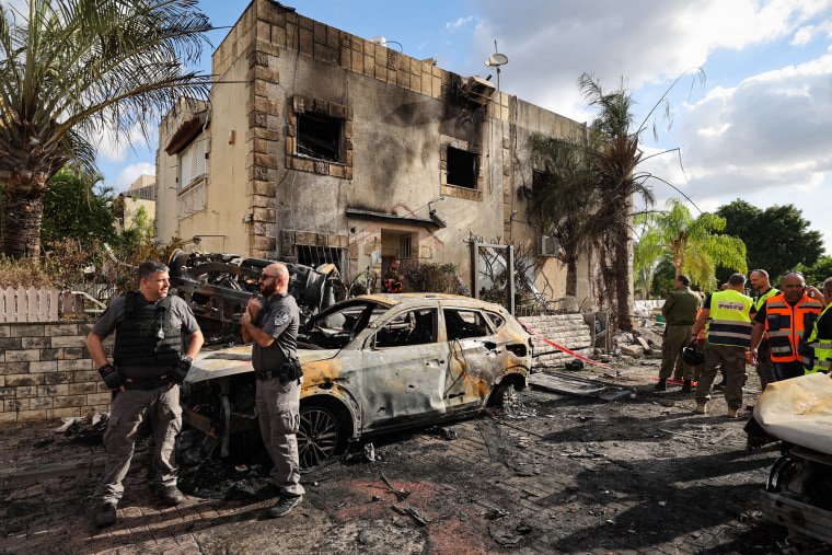 First responders and security forces gather amid debris and charred vehicles outside