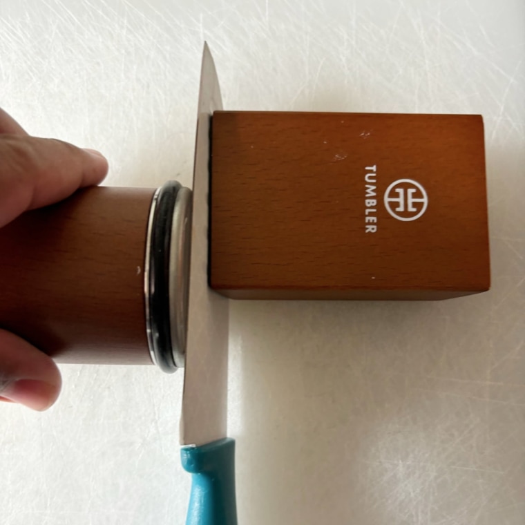 Dull knife attached to the Tumbler knife sharpener on a cutting board.