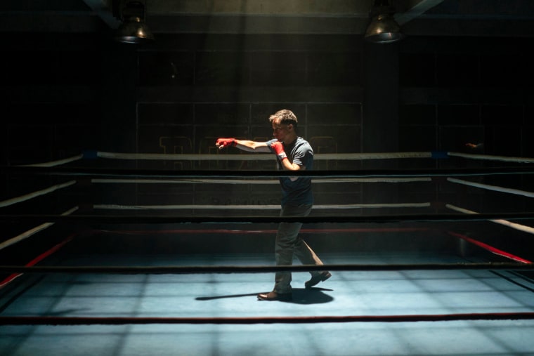 Diego Luna throws a punch in the air in a fighting ring