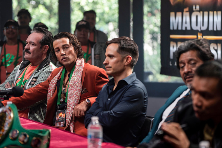 Five people sit in a row at a table during a conference