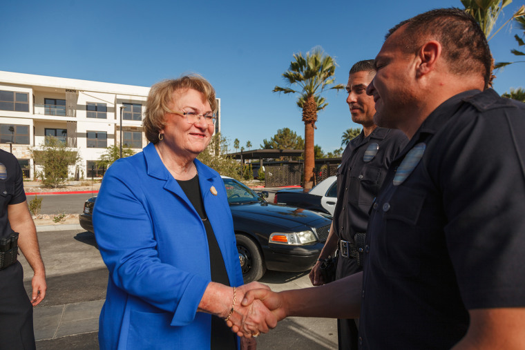 Photo of subject Lisa Middleton in a blue suit shaking hands with a police officer 