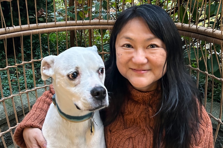 JaeRan Kim sits next to a white dog on her left.