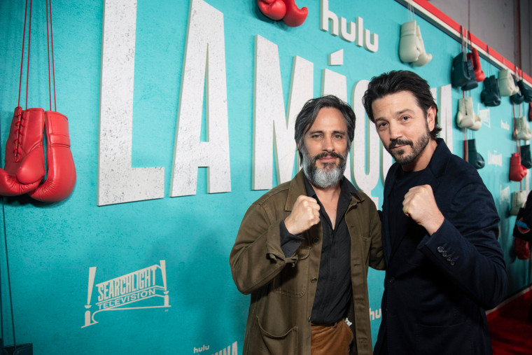 Gael Garcia Bernal, left, and Diego Luna pose for a photo together on the red carpet, holding up their fists