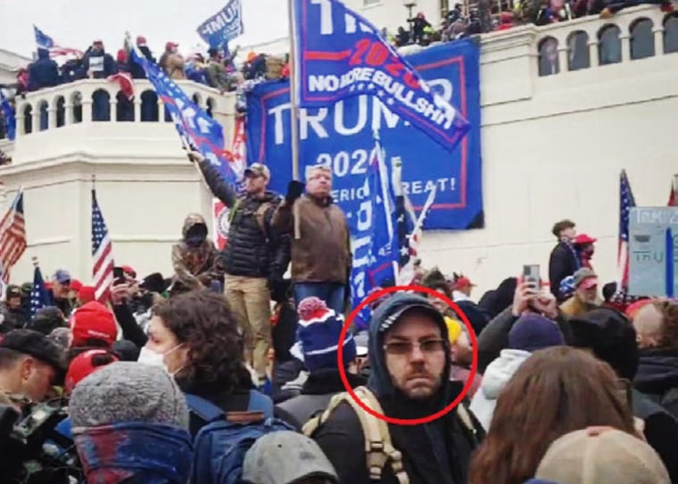 Jonathn Newcomb at the Capitol on Jan. 6, 2021, with a banner in the background brought by him.