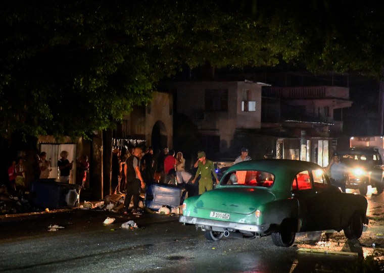 Cuban police remove debris used to block a street during a protest against a blackout, in Havana