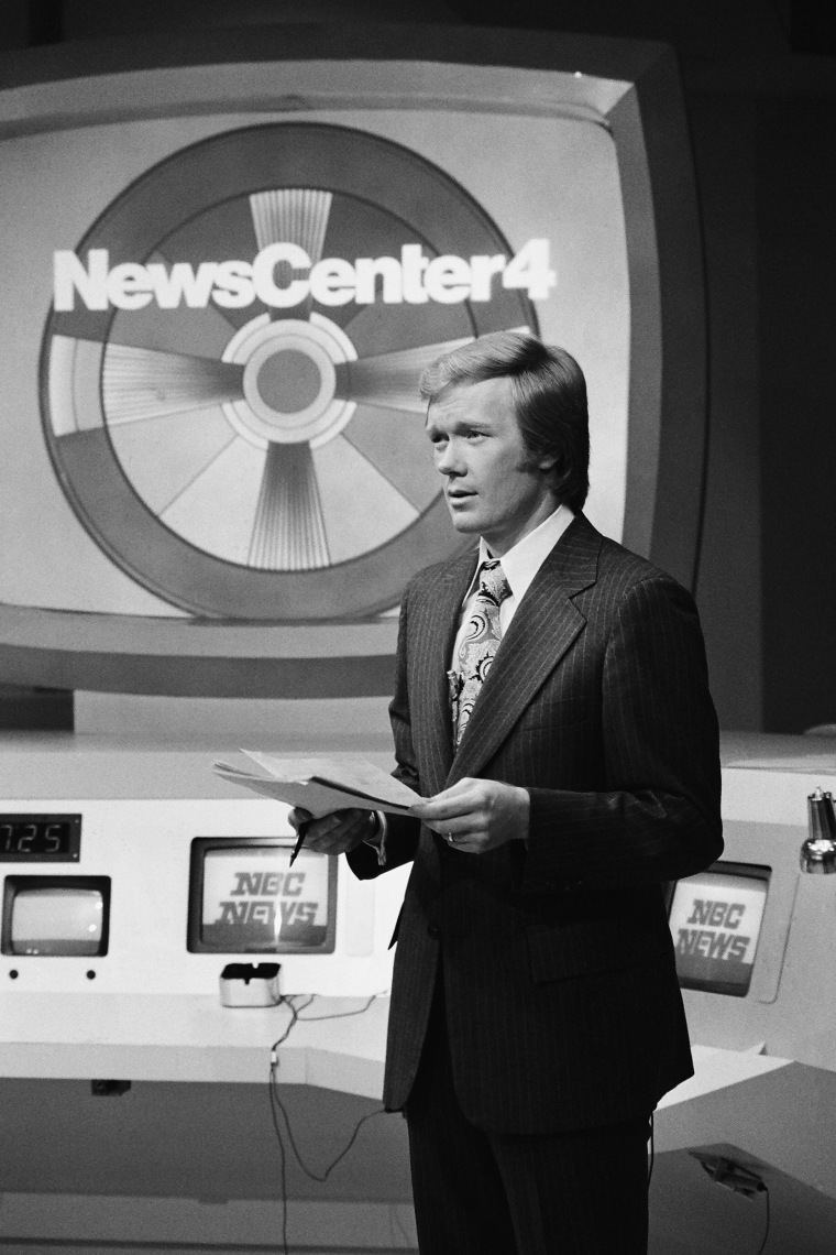 A black and white photo of Chuck Scarborough in front of a NewsCenter4 sign